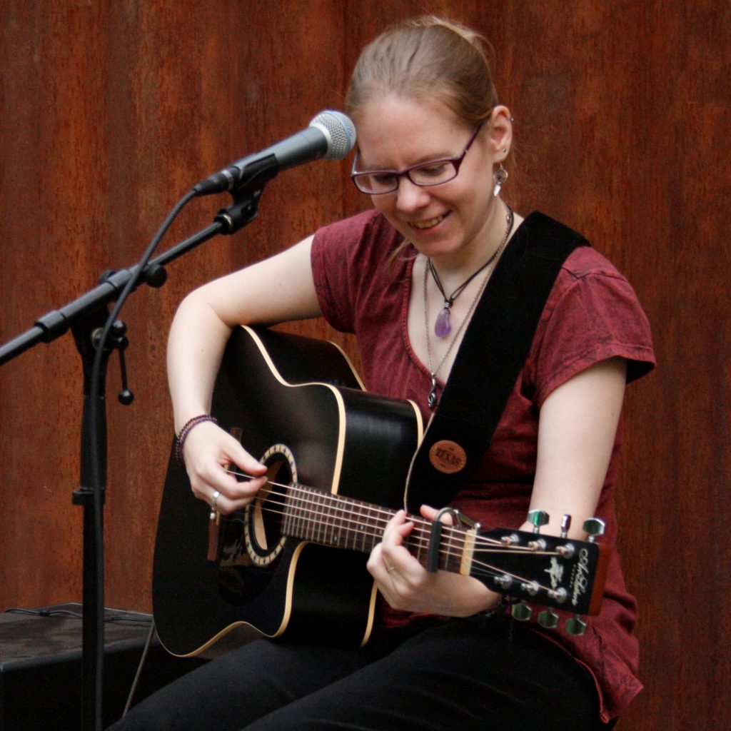 Jessica Mahnke spielt live mit Akustikgitarre und singt Folksongs aus den 60er Jahren